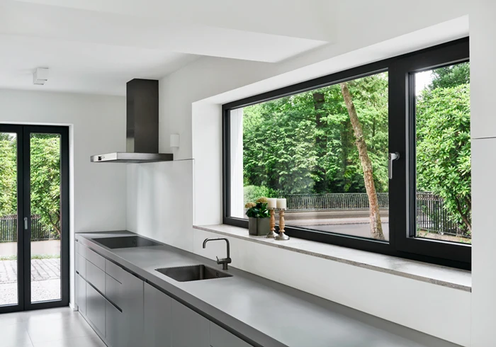 Finestra in alluminio antracite sopra il piano di una cucina, aperta sul giardino